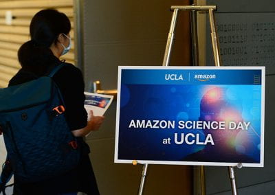 Young woman guest viewing Amazon Science Day at UCLA sign before start of event